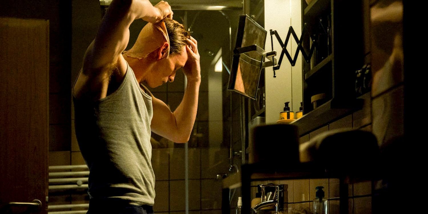 Jackal (Eddie Redmayne) putting on a latex mask in The Day of the Jackal