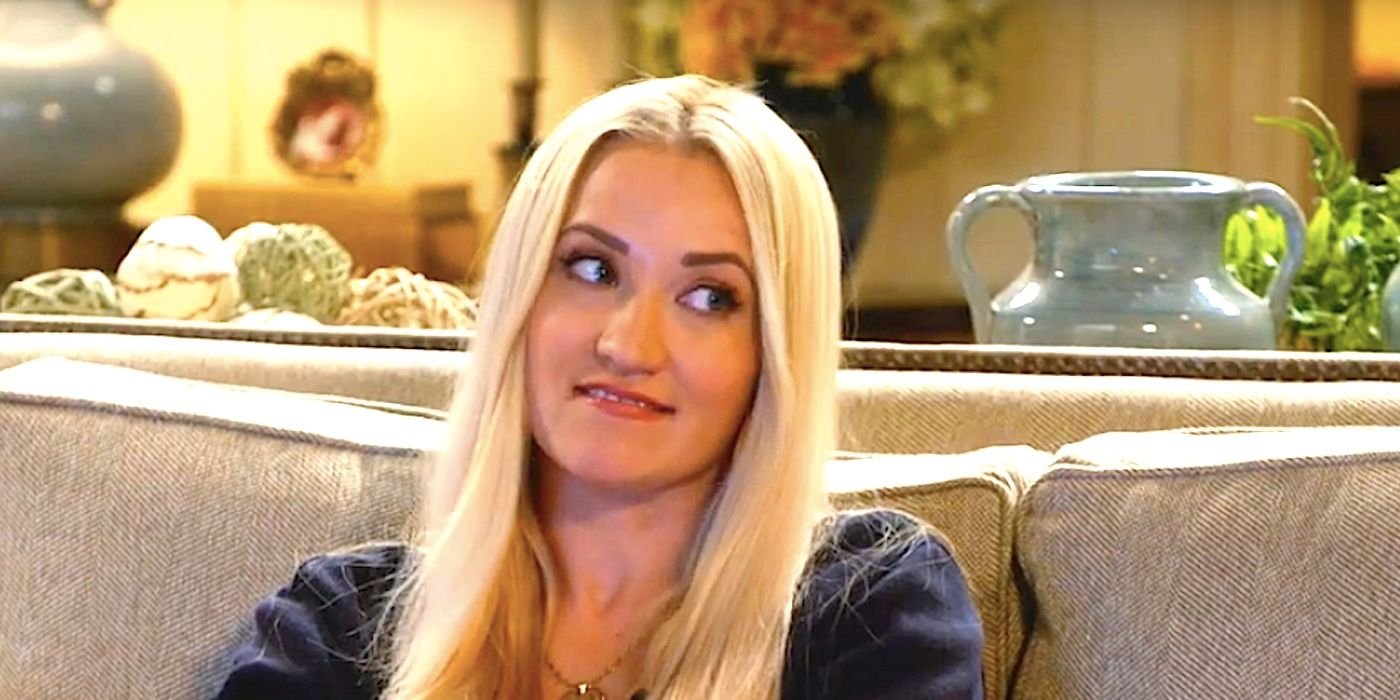 Emily Osment's Mandy smiles while sitting on the couch in Georgie & Mandy's First Marriage trailer