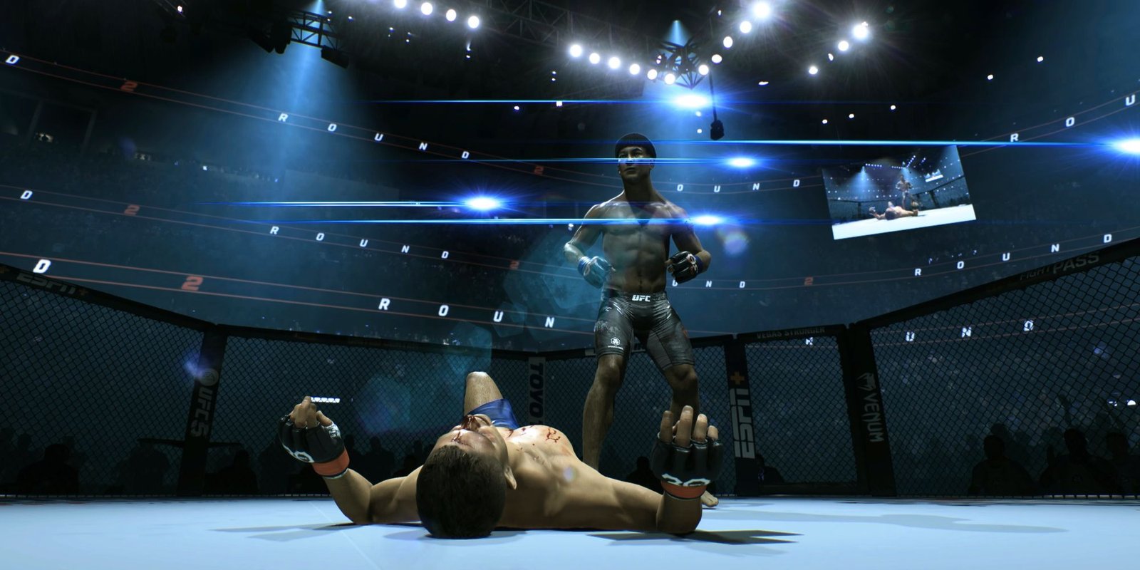 Screenshot from UFC 5 shows custom character towering over a defeated opponent in the octagon while lights reflect from the rafters and the crowd is obscured by fog and shadows.