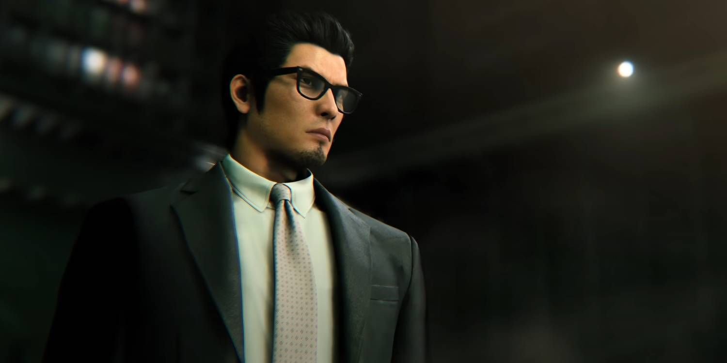 Kazuma Kiryu wearing a dark suit and tie, standing in a dark room