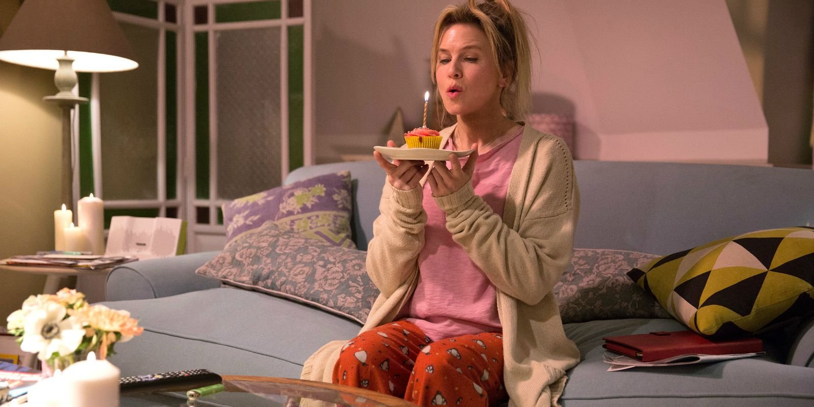 Bridget blows out a candle while sitting on a bed in Bridget Jones's Baby