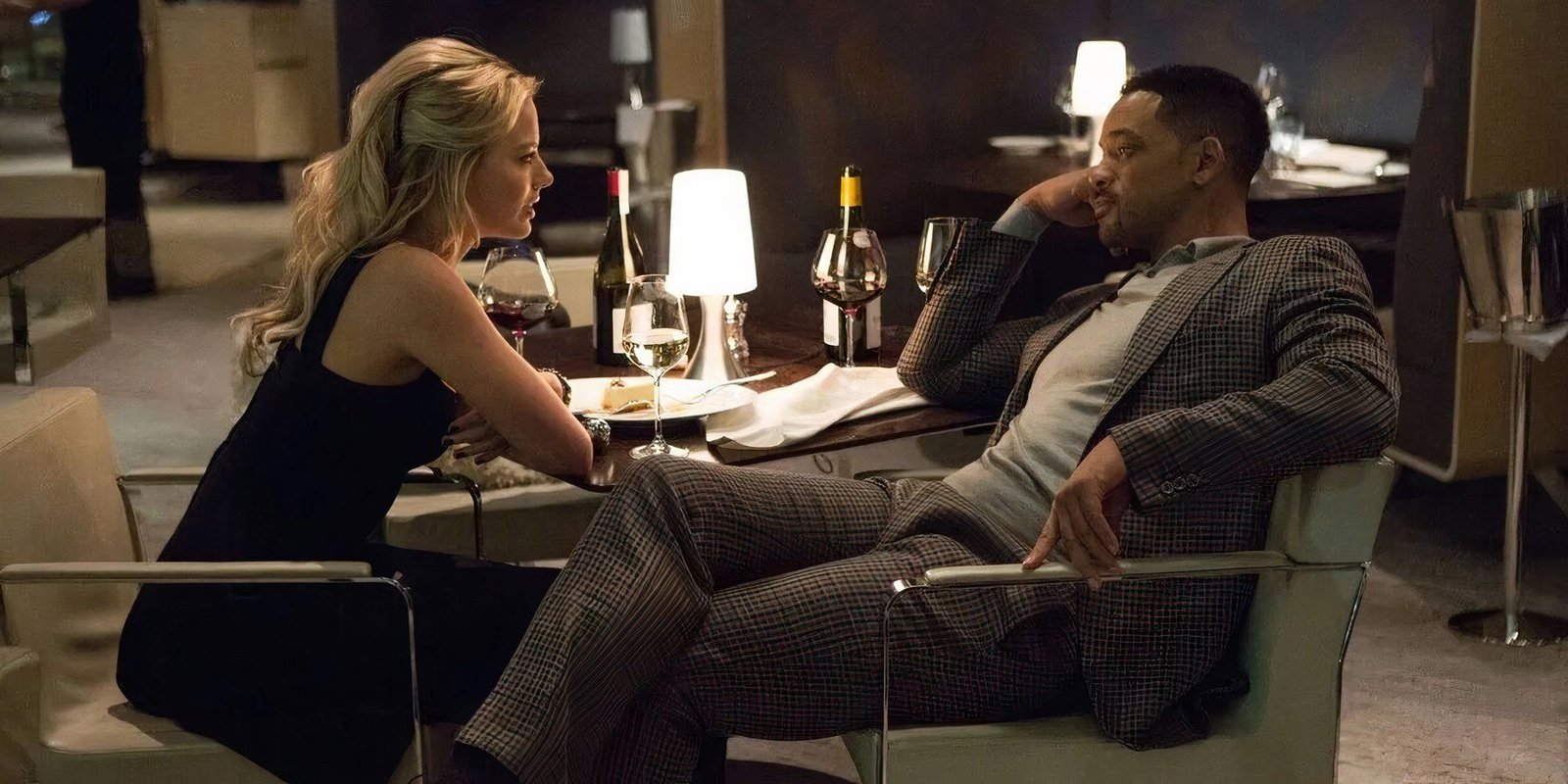 Will Smith and Margot Robbie in Focus (2015) sitting across from each other in a hotel