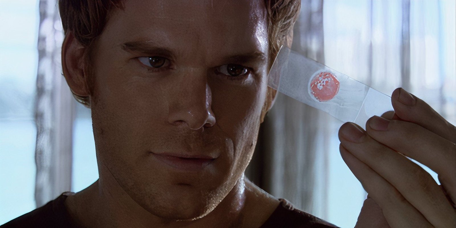 Dexter Morgan (Michael C. Hall) grinning at a blood slide in Dexter season 1, episode 1