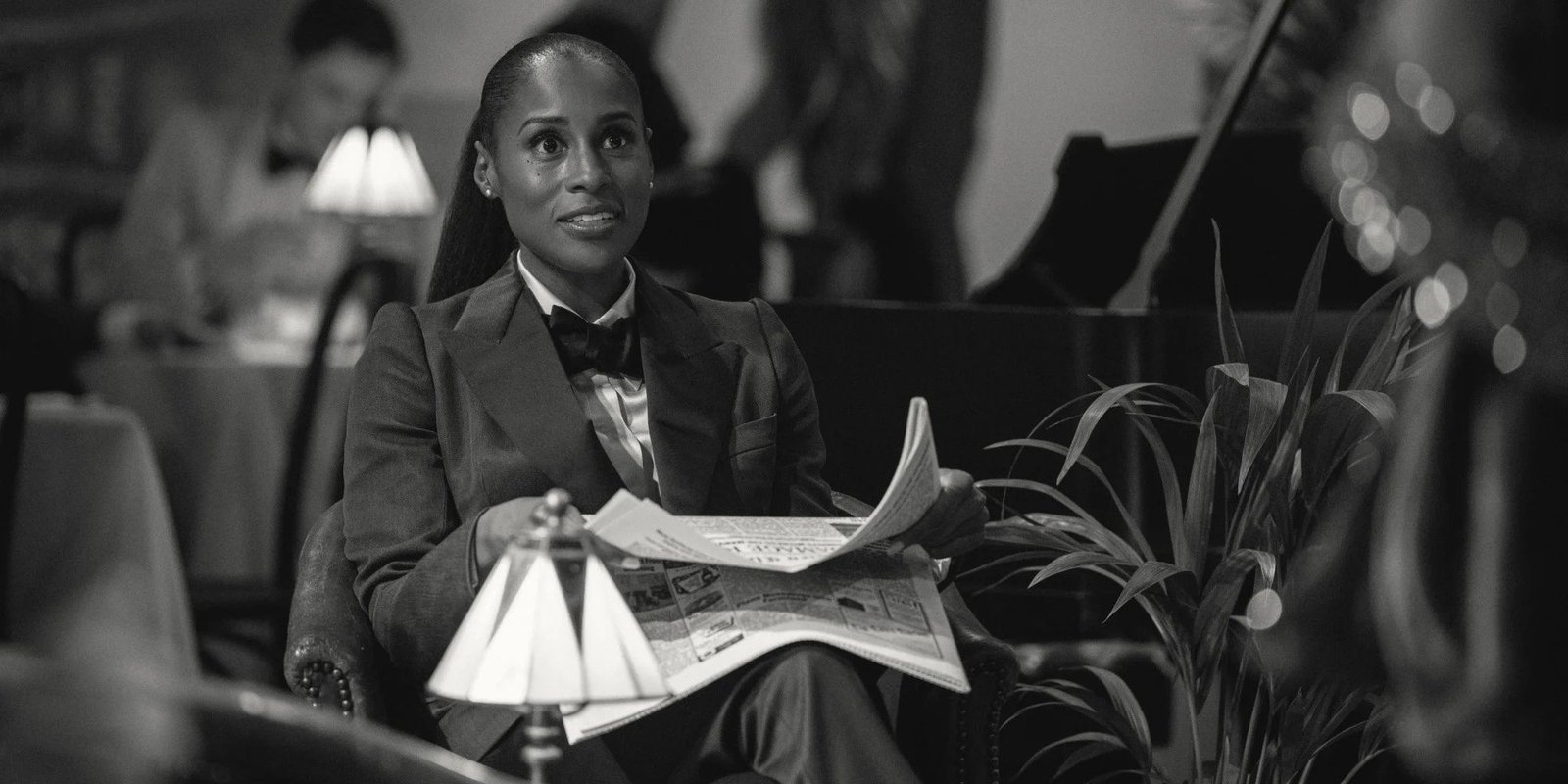 Brandy (Issa Rae) as Dr. Alex Palmer smiling and holding a newspaper in "Hotel Reverie"