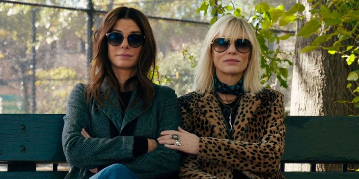 Sandra Bullock and Cate Blanchett sitting in a park in Ocean's 8