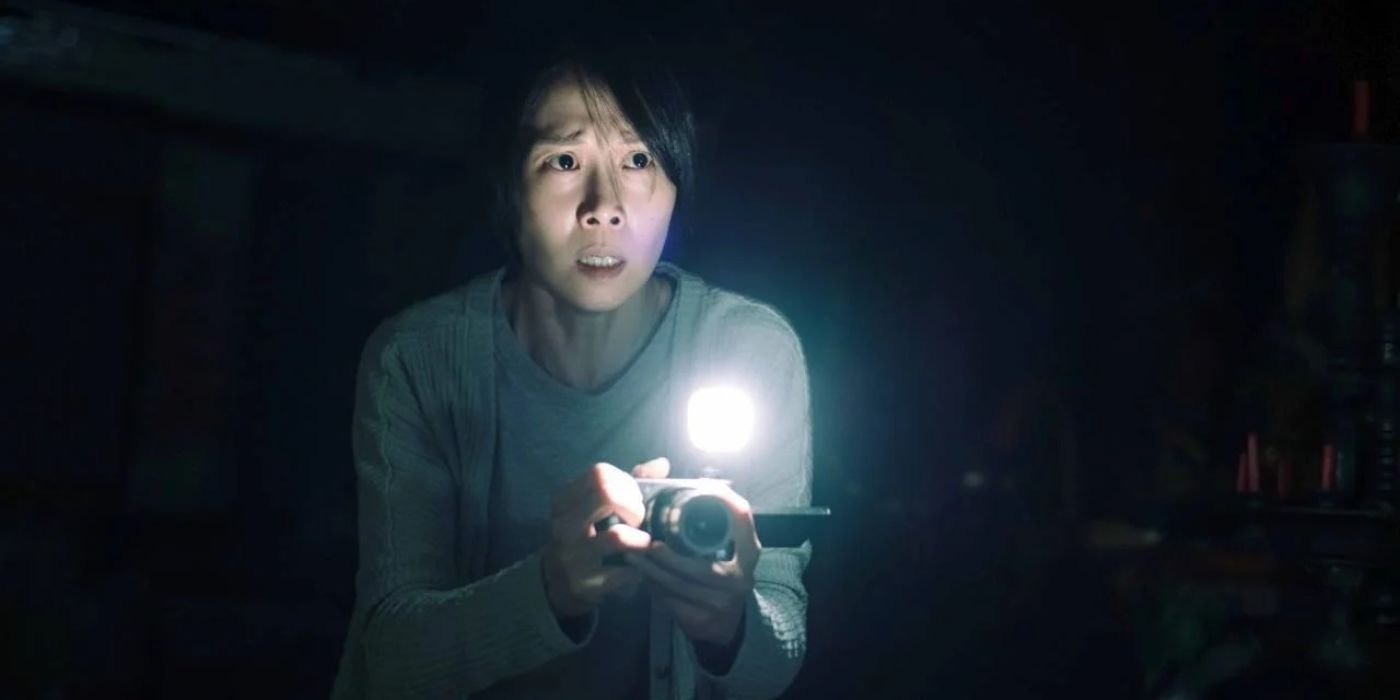 Li Ronan (Tsai Hsuan-yen) shining a flashlight and looking scared in Incantation.