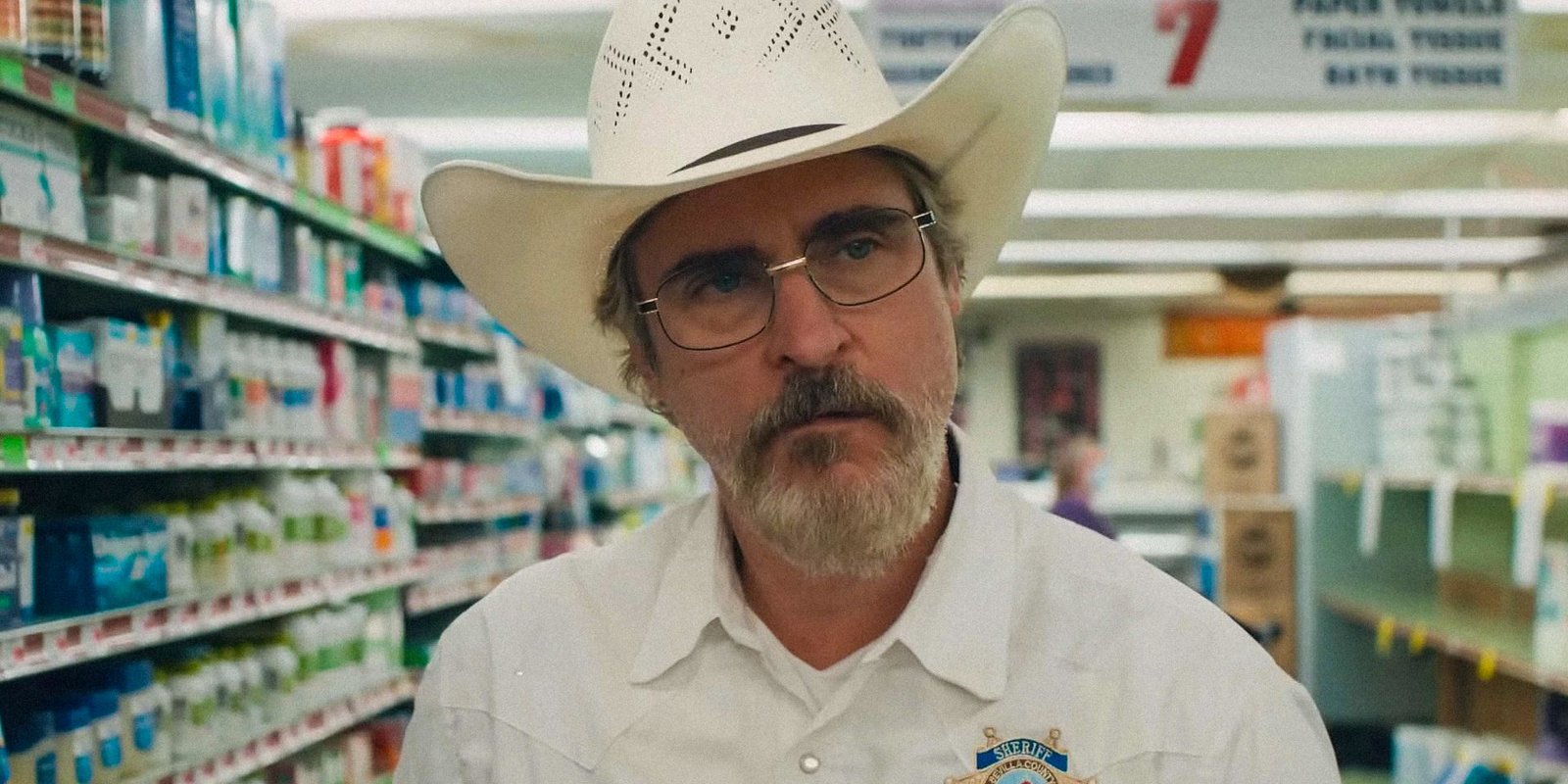 Joaquin Phoenix as Joe Cross looking quizzical in a store aisle in Eddington