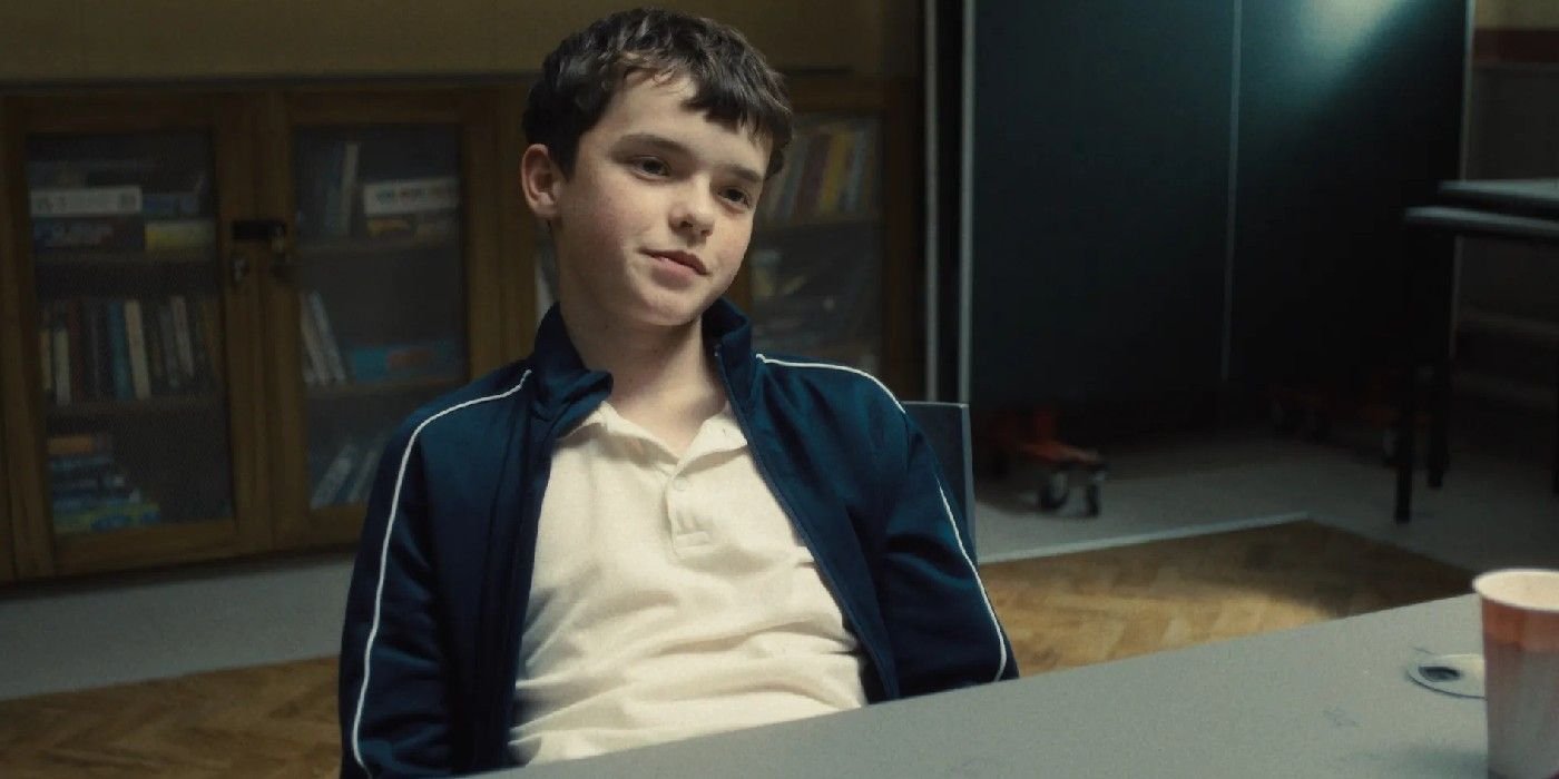 Owen Cooper as Jamie Miller sitting at a table in Adolescence