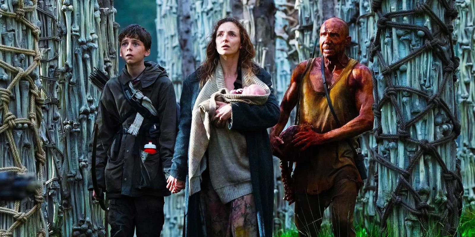 Alfie Williams as Spike, Jodie Comer as Isla, and Ralph Fiennes as Dr. Kelson standing in the Bone Temple in 28 Years Later