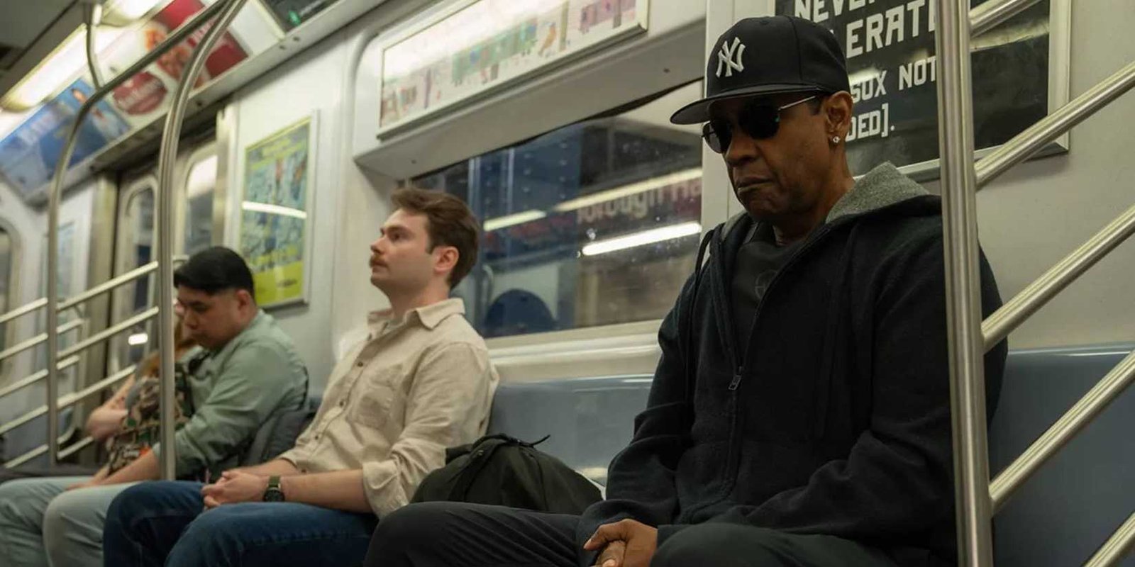 Denzel Washington sitting on the subway with sunglasses and baseball hat in Highest 2 Lowest