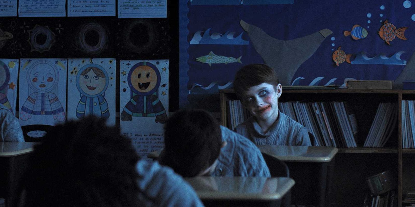 Alex smiling in overdone makeup as classmates sleep on their desks in Weapons