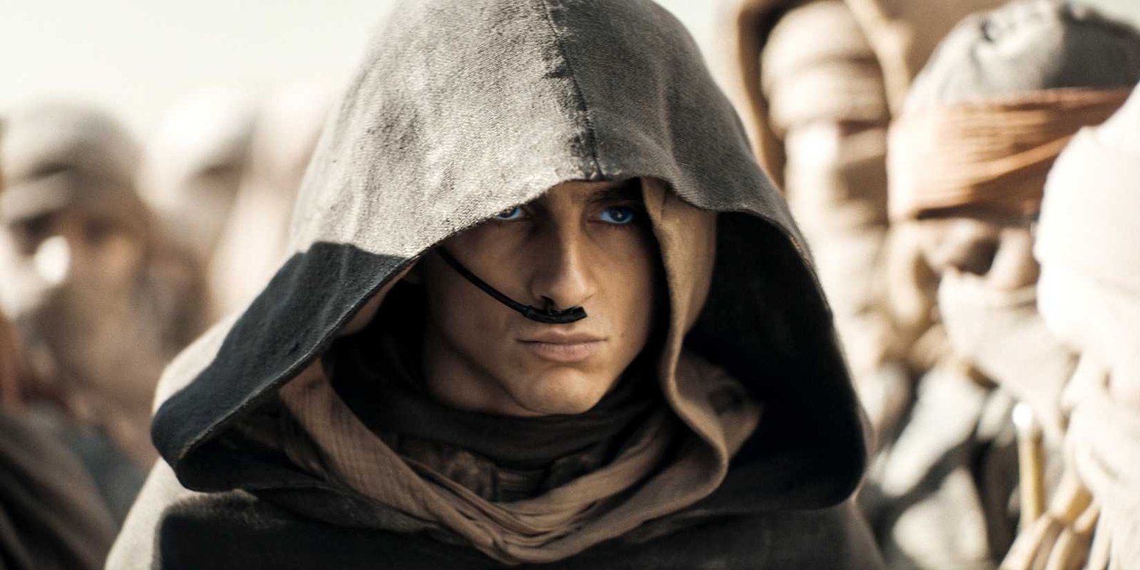 Paul Atreides standing among the Fremen with his hood up in Dune Part Two